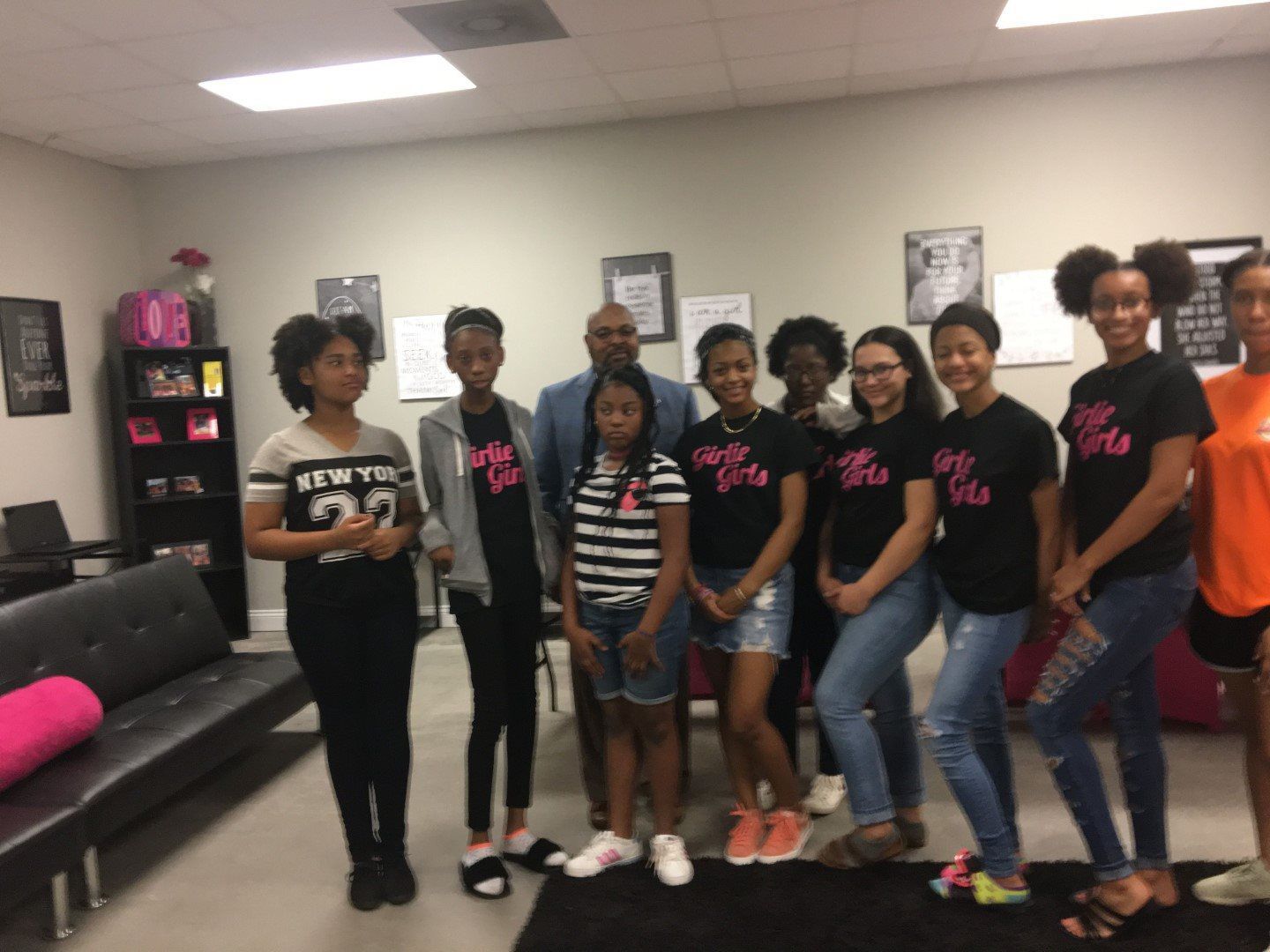 A group of young girls are posing for a picture in a room.