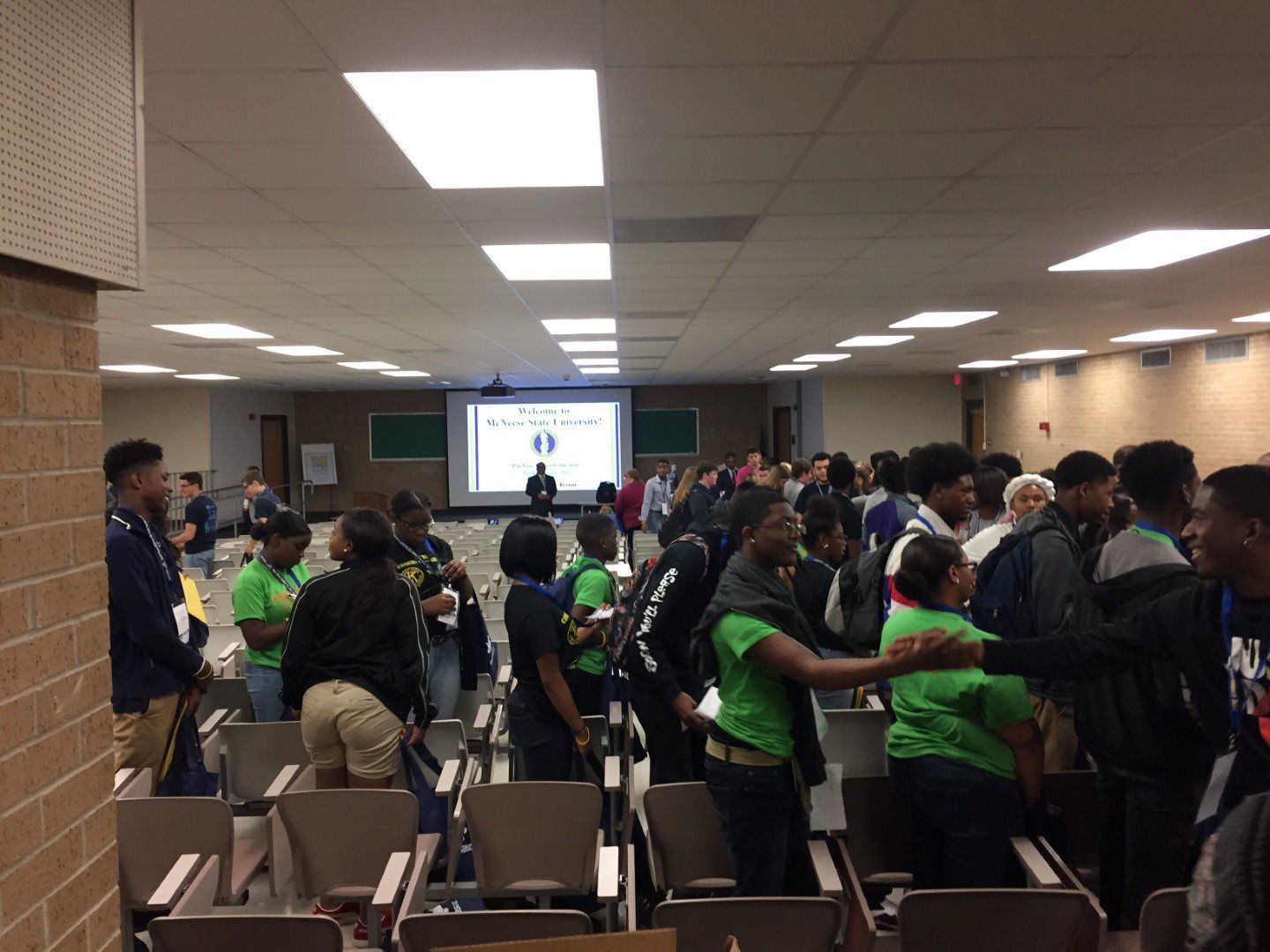 A group of people standing in a room with a projector screen
