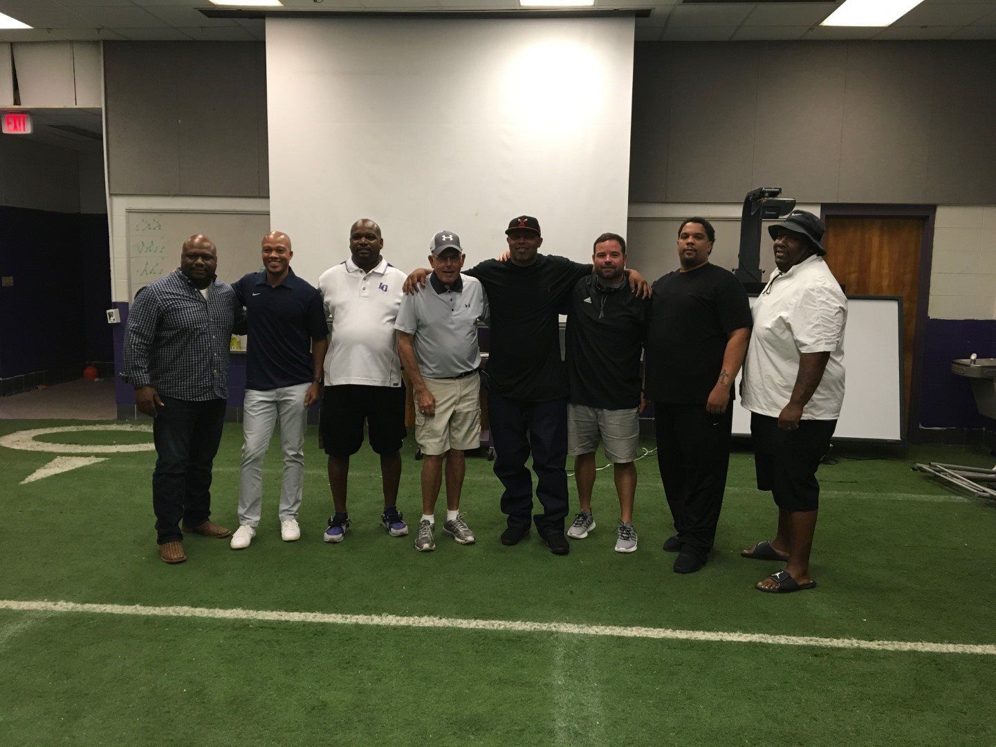 A group of men are posing for a picture on a football field.