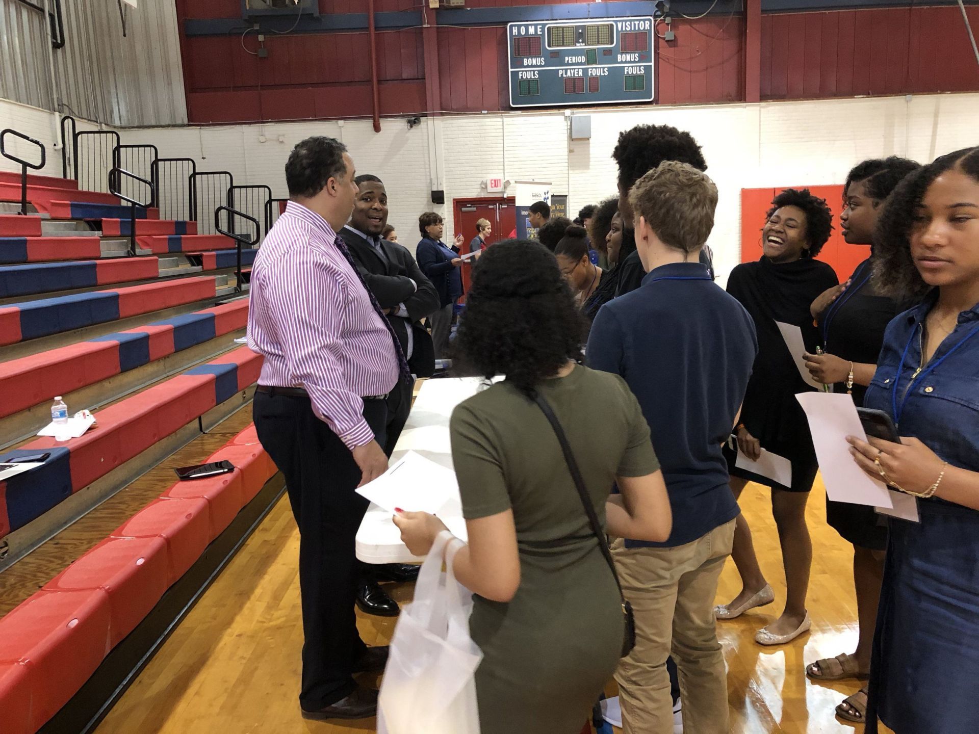 A group of people are standing around a table in a gym.