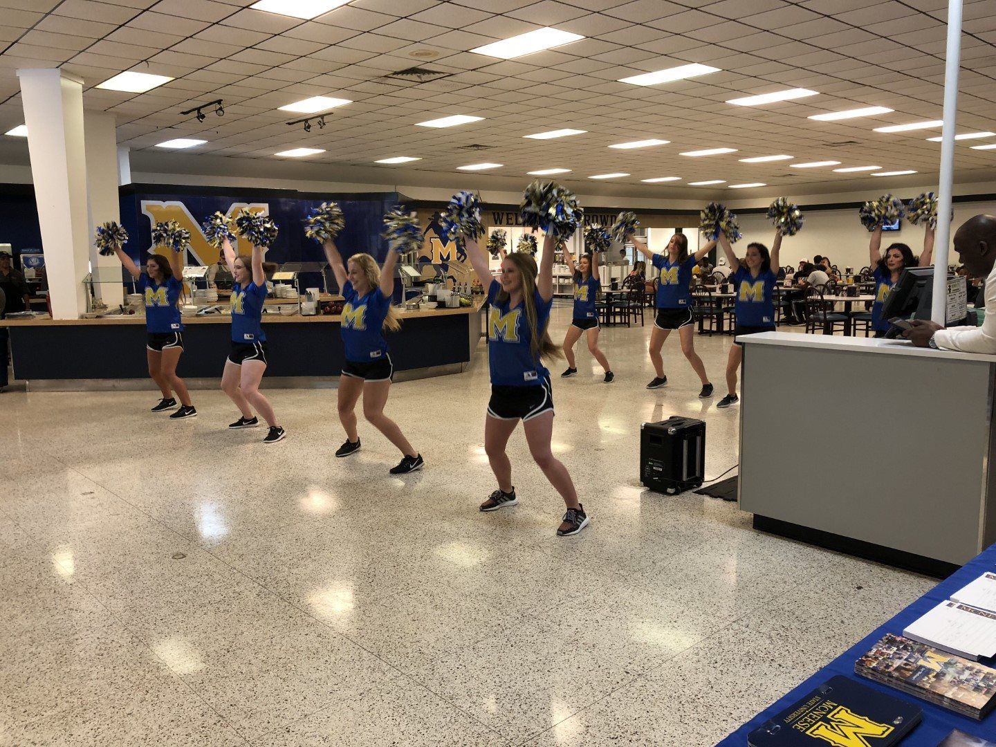 A group of cheerleaders are dancing in a gym.