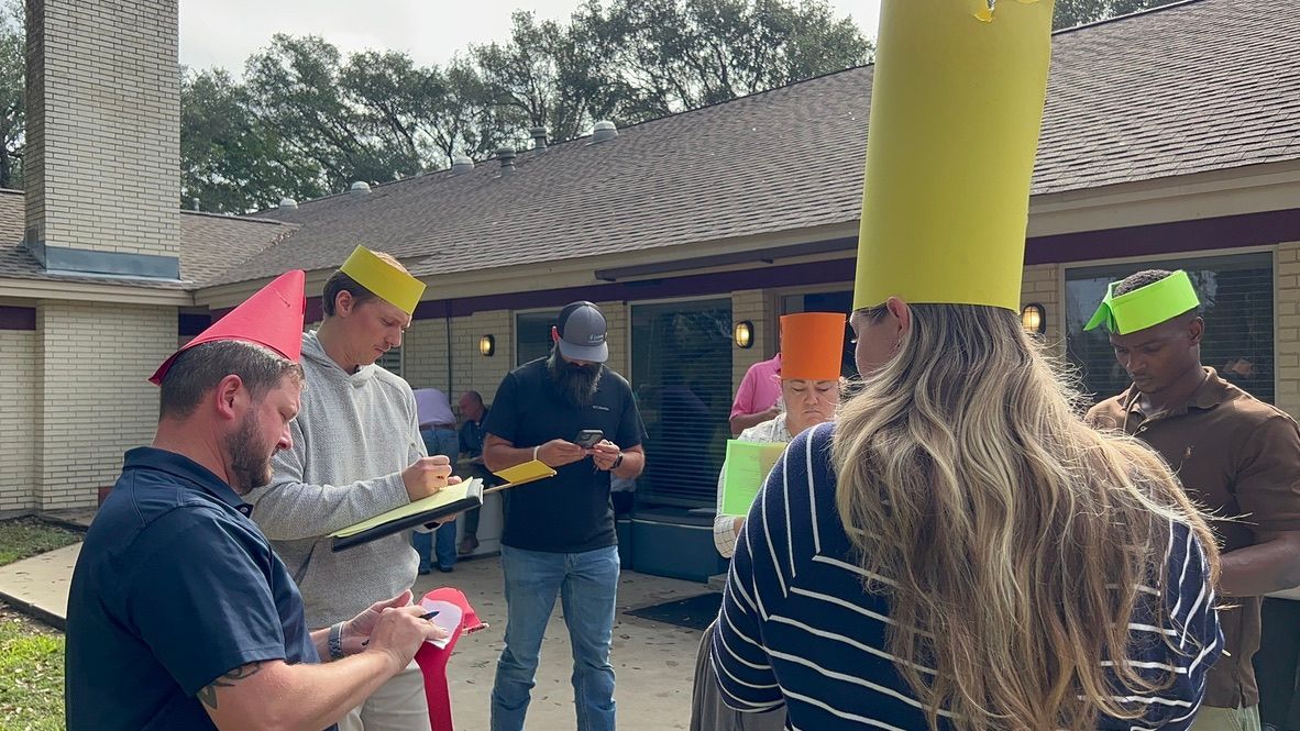 A group of people wearing paper hats are standing in front of a house.