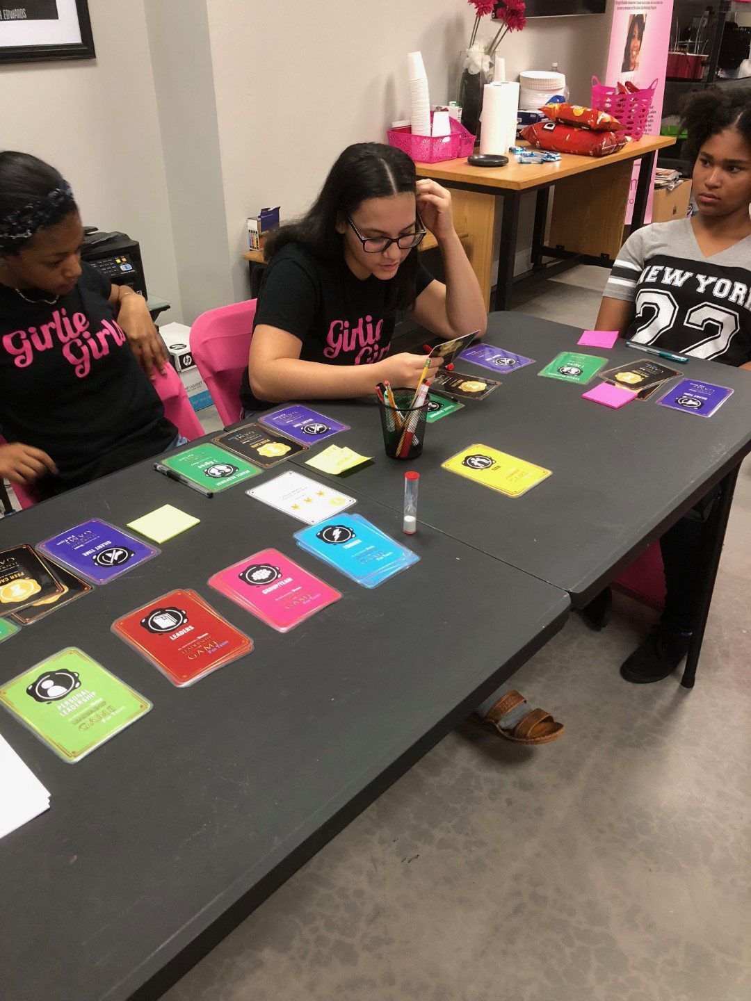A group of girls are sitting at a table playing a game.