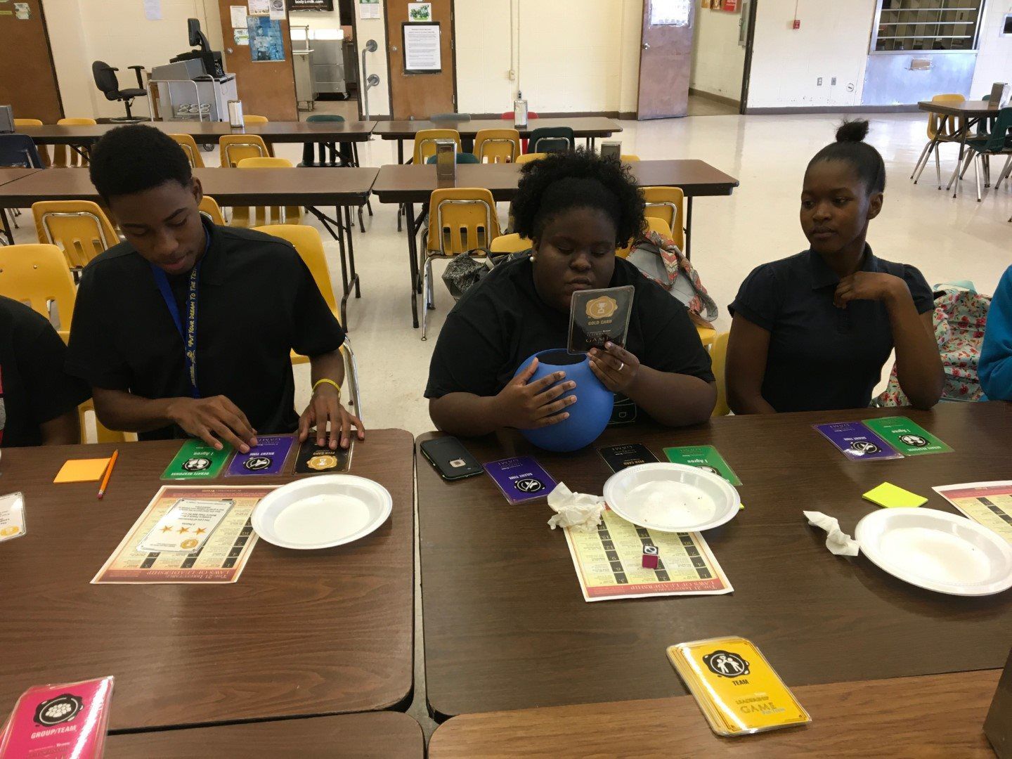 A group of young people are sitting at a table playing a game.