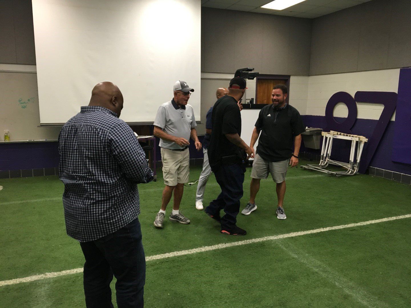 A group of men are standing on top of a football field.