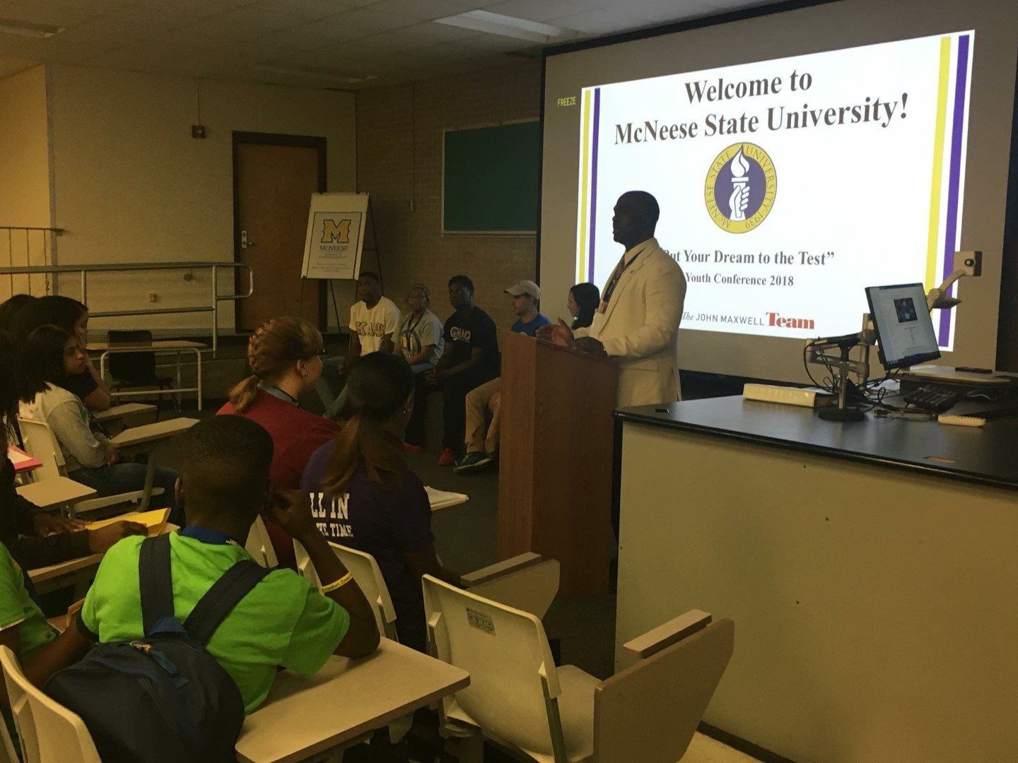 A man is giving a presentation to a group of people in a classroom.