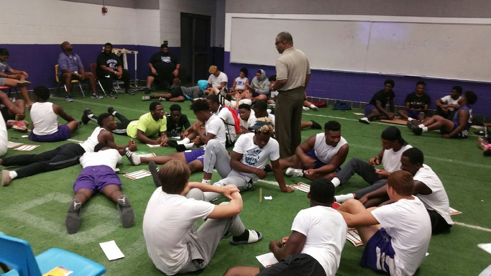A group of young men are sitting in a circle on the grass