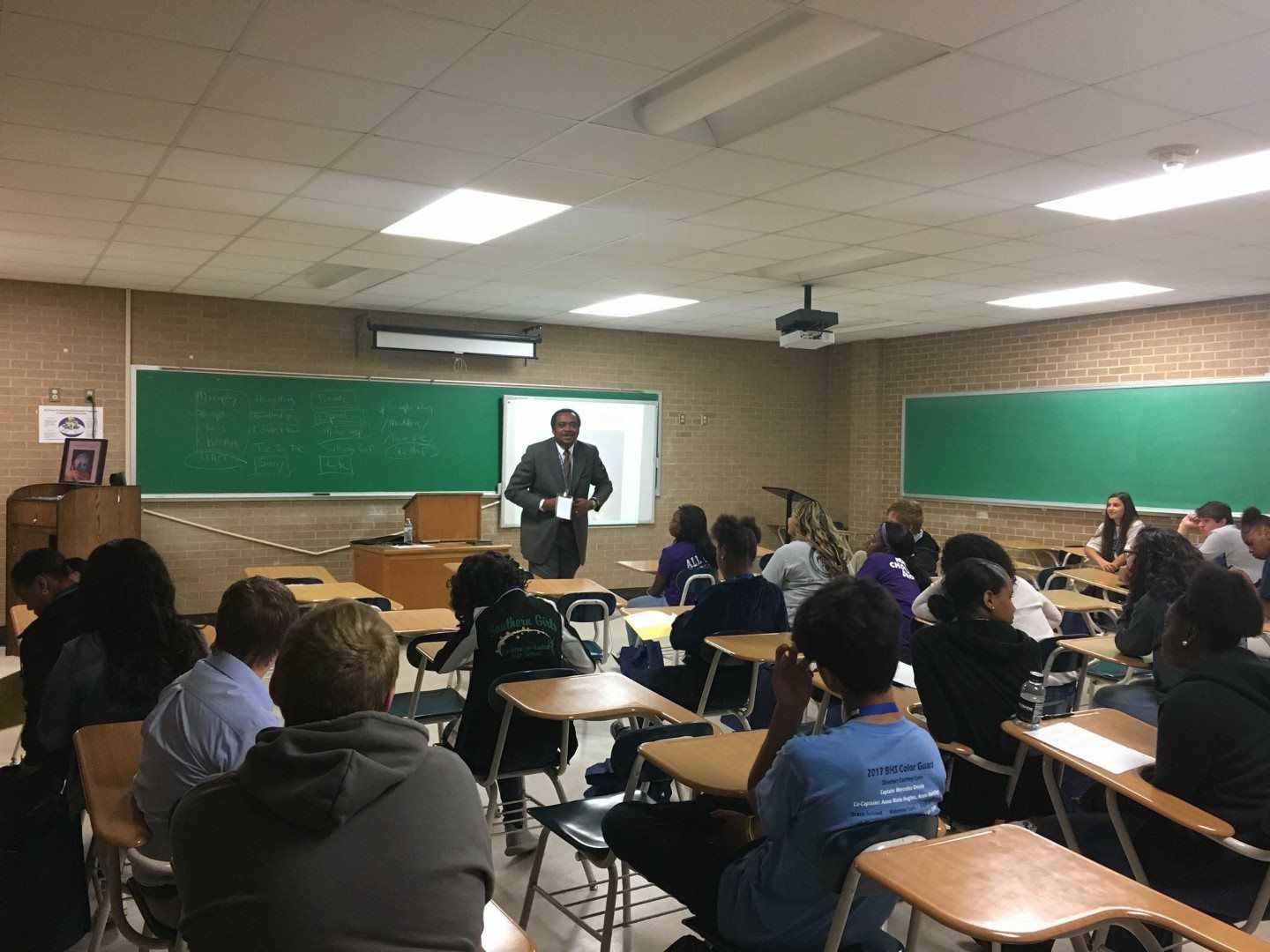 A man is giving a presentation to a group of students in a classroom.