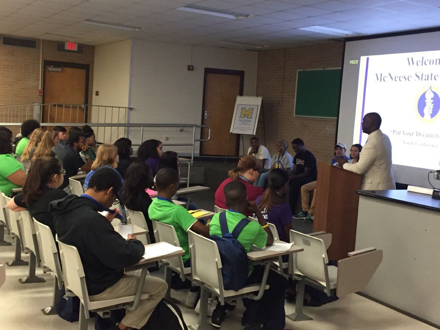 A man is giving a presentation to a group of people in a classroom.