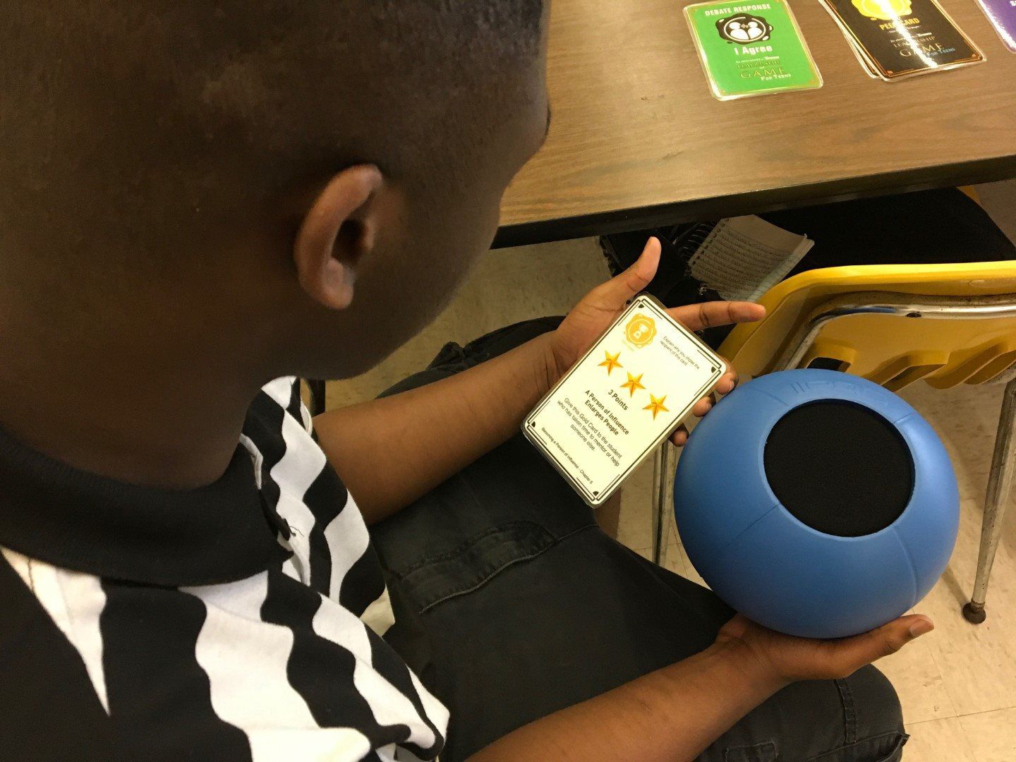 A boy is holding a blue speaker and a cell phone