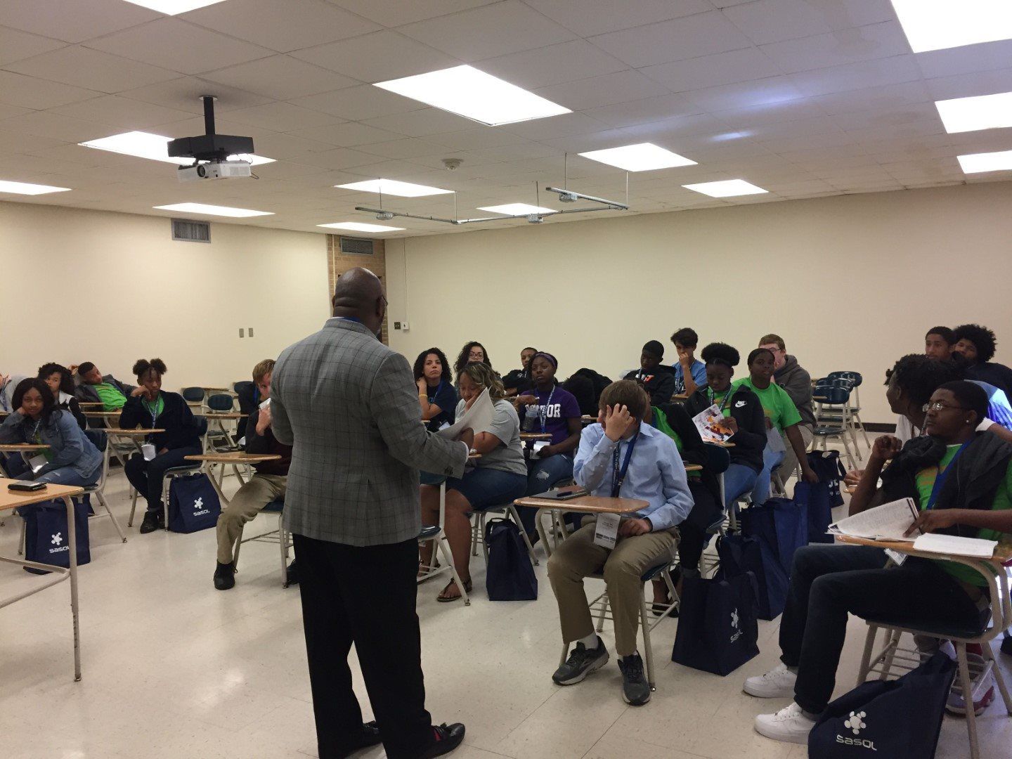A man is standing in front of a classroom full of students.