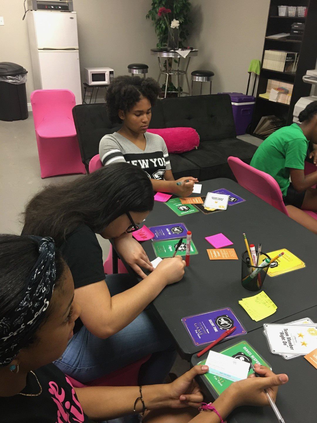 A group of girls are sitting around a table with sticky notes on it