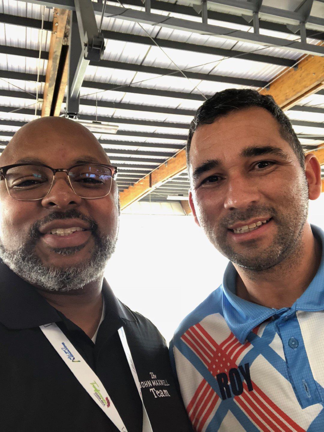 Two men are posing for a picture together in a building.