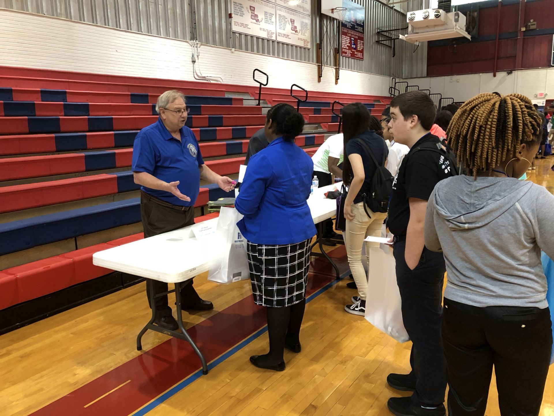 A man is talking to a group of people in a gym.