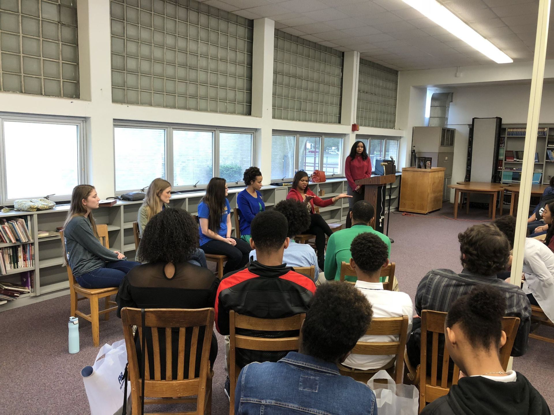 A group of people are sitting in a circle in a library.