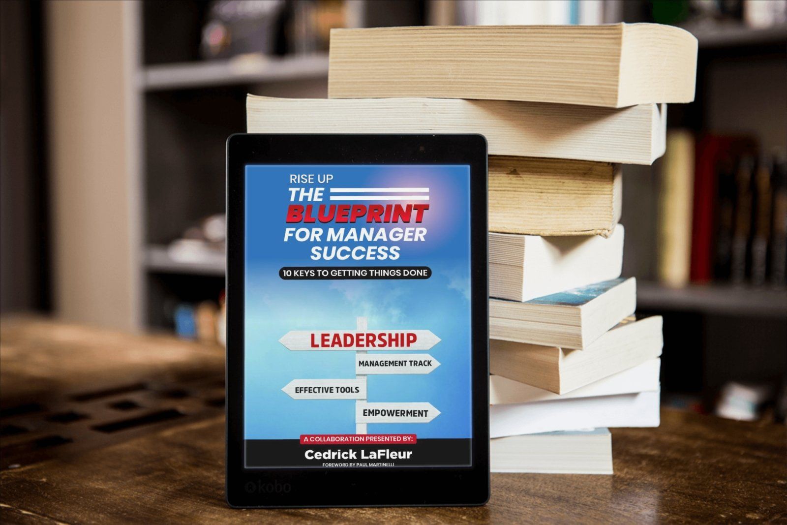 A tablet is sitting on top of a stack of books titled the blueprint for manager success
