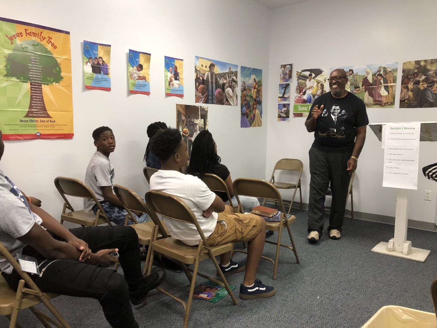 A man is standing in front of a group of people sitting in chairs.