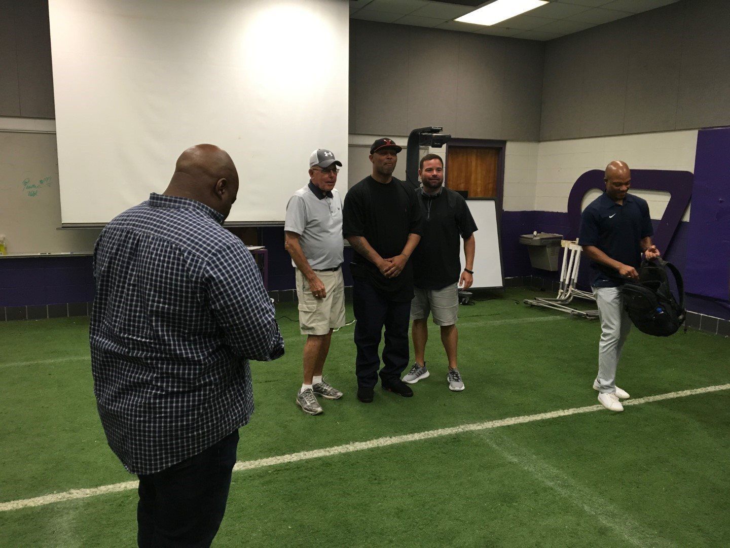 A group of men are standing on a football field.