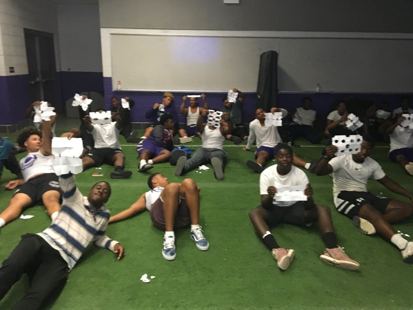 A group of people are laying on the grass holding up numbers 88