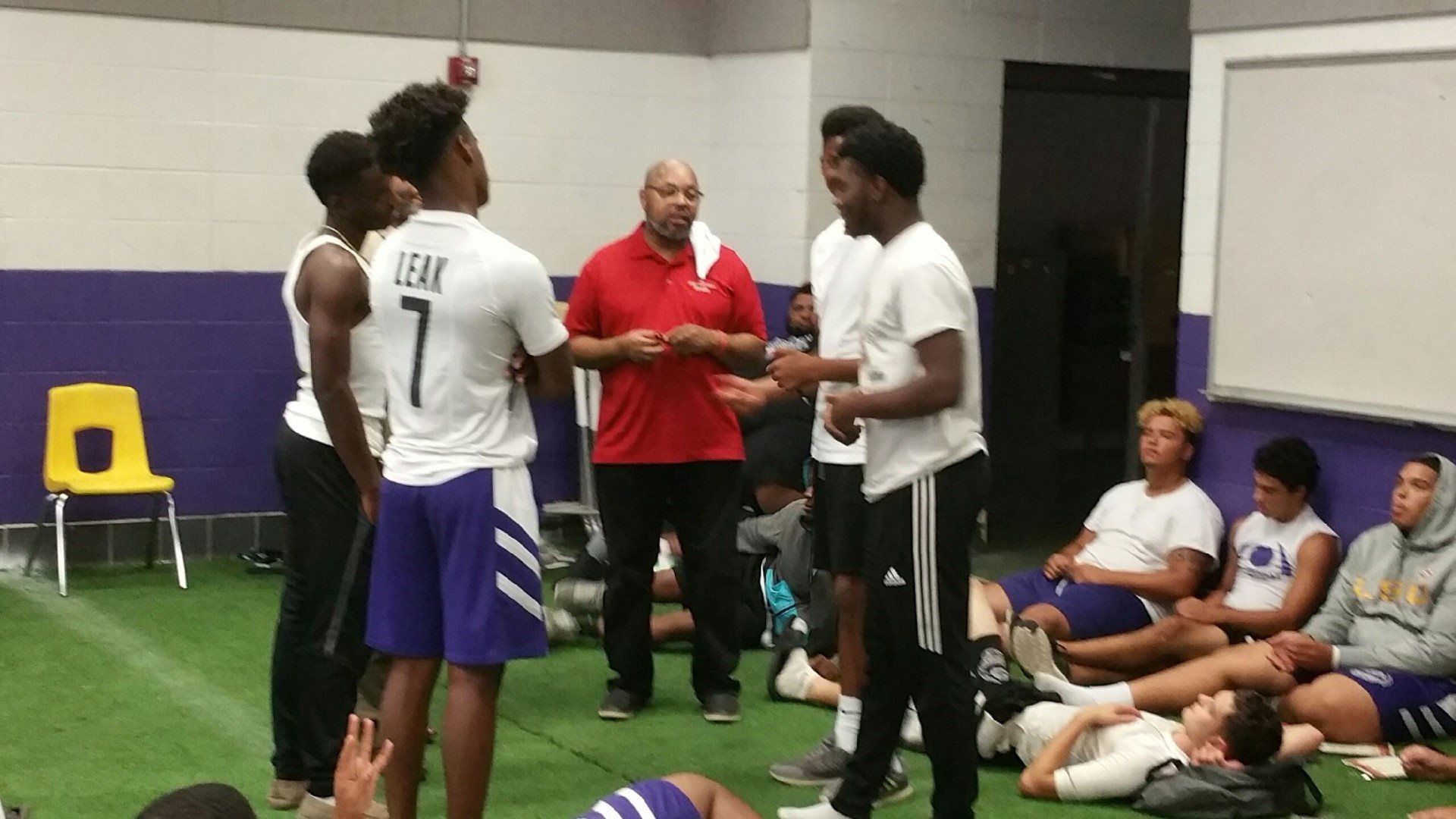 A group of young men are standing in a room talking to each other.