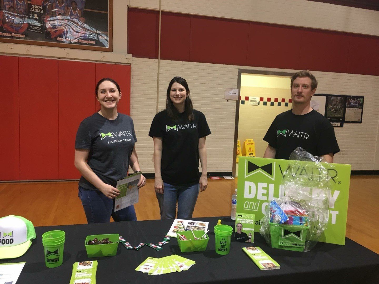 A group of people are standing around a table in a gym.