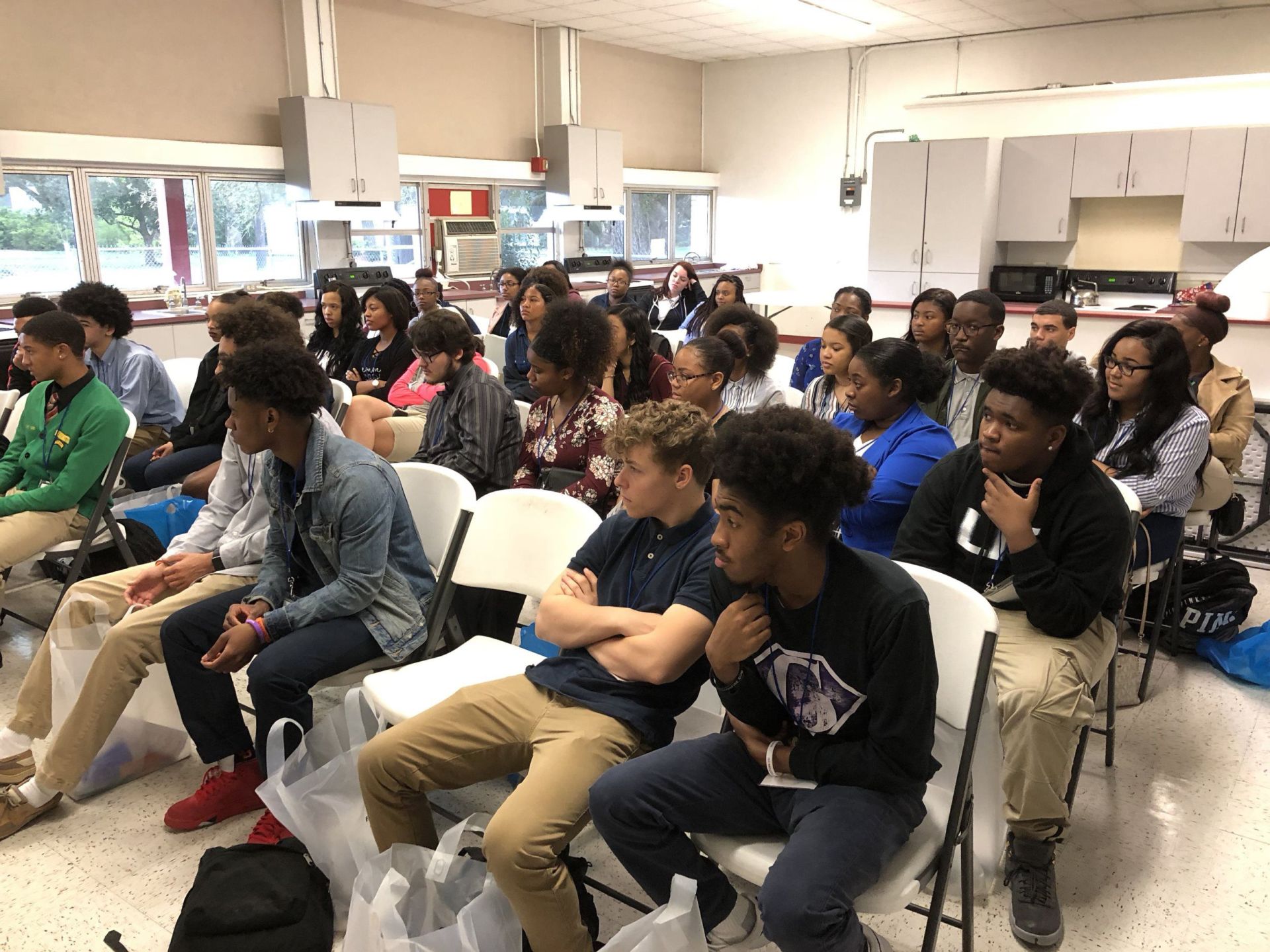 A group of young people are sitting in chairs in a room.