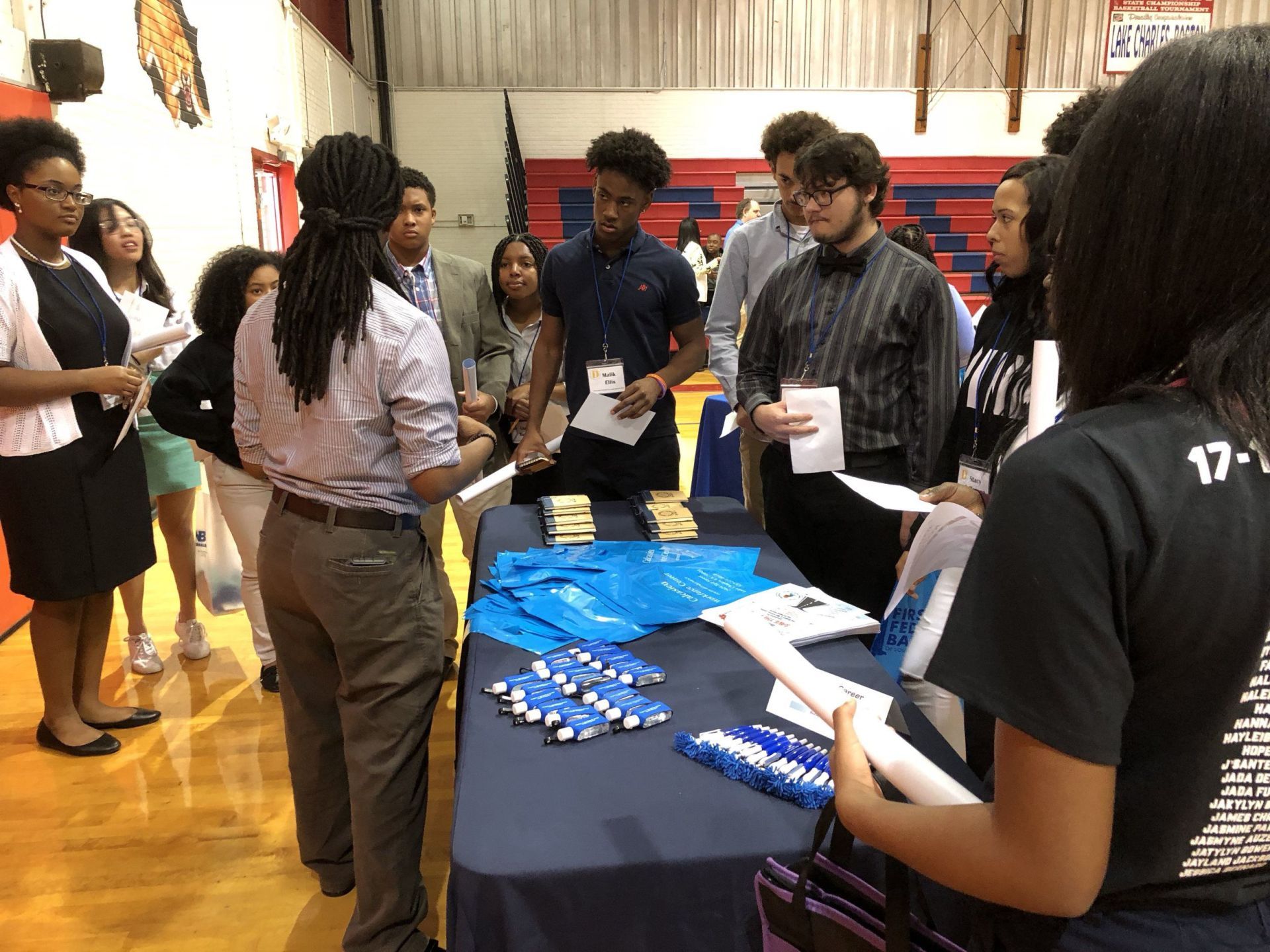 A group of people are standing around a table at a job fair.