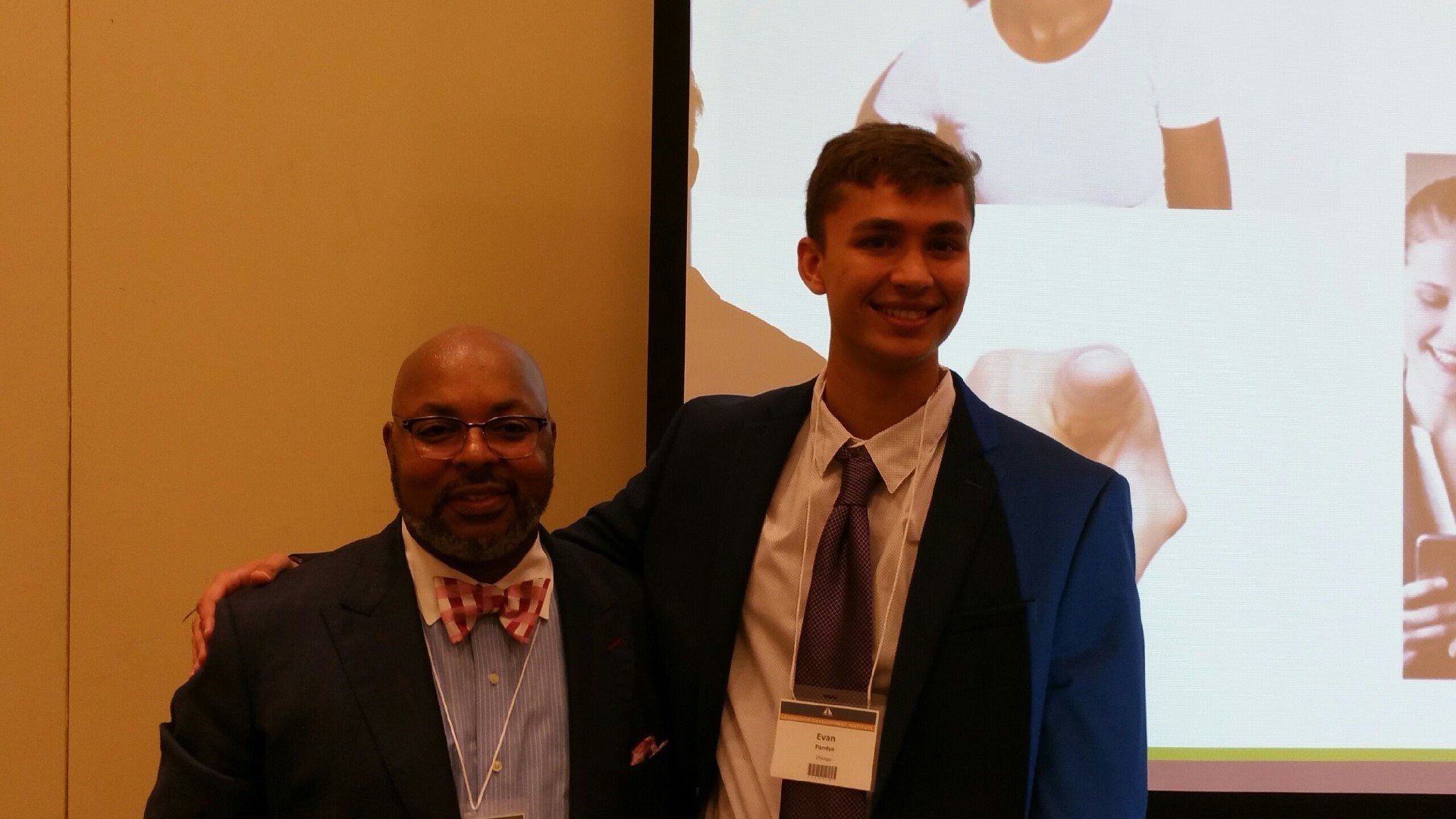 Two men in suits and bow ties are posing for a picture.