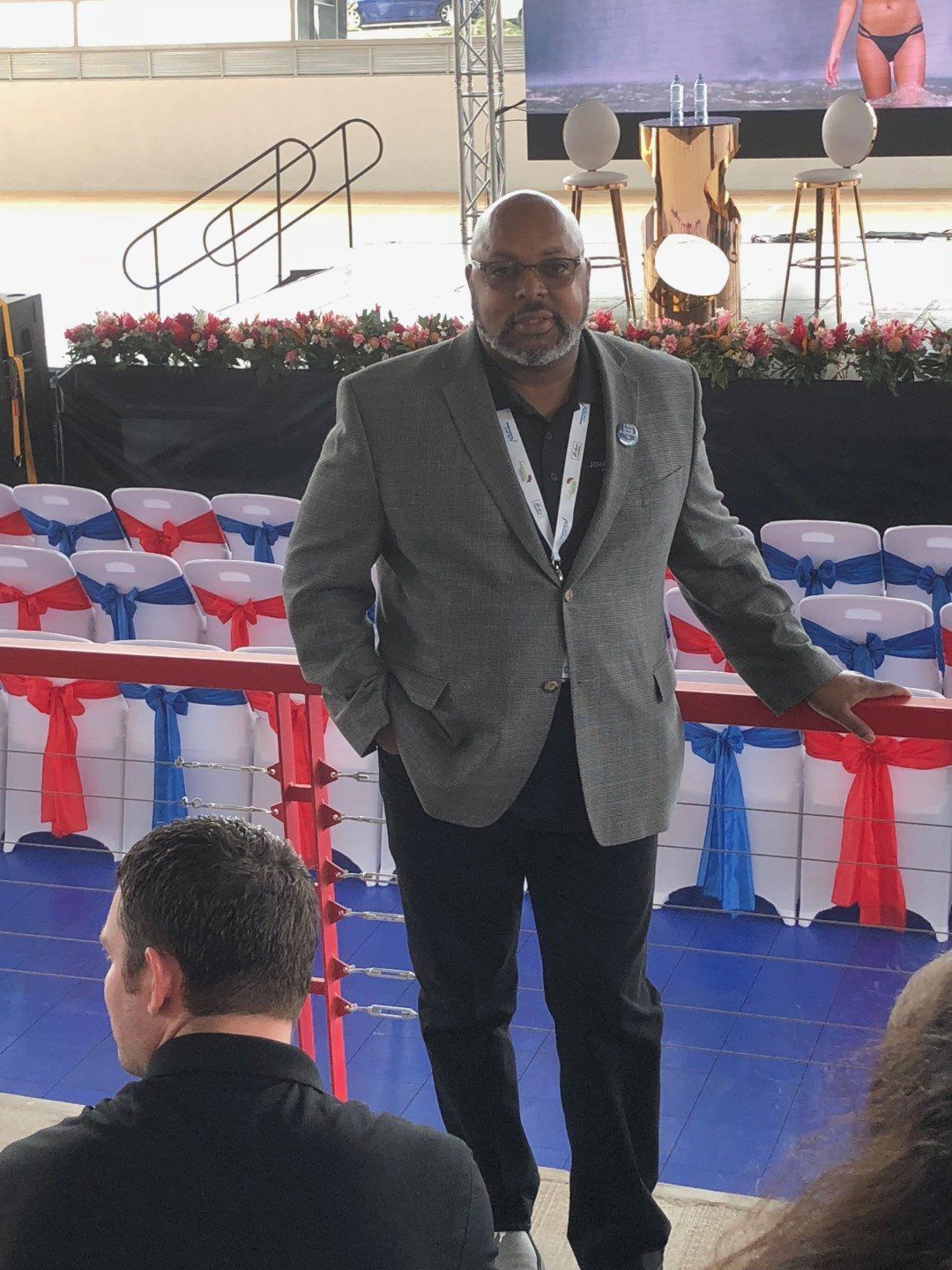 A man in a suit is standing in front of rows of chairs