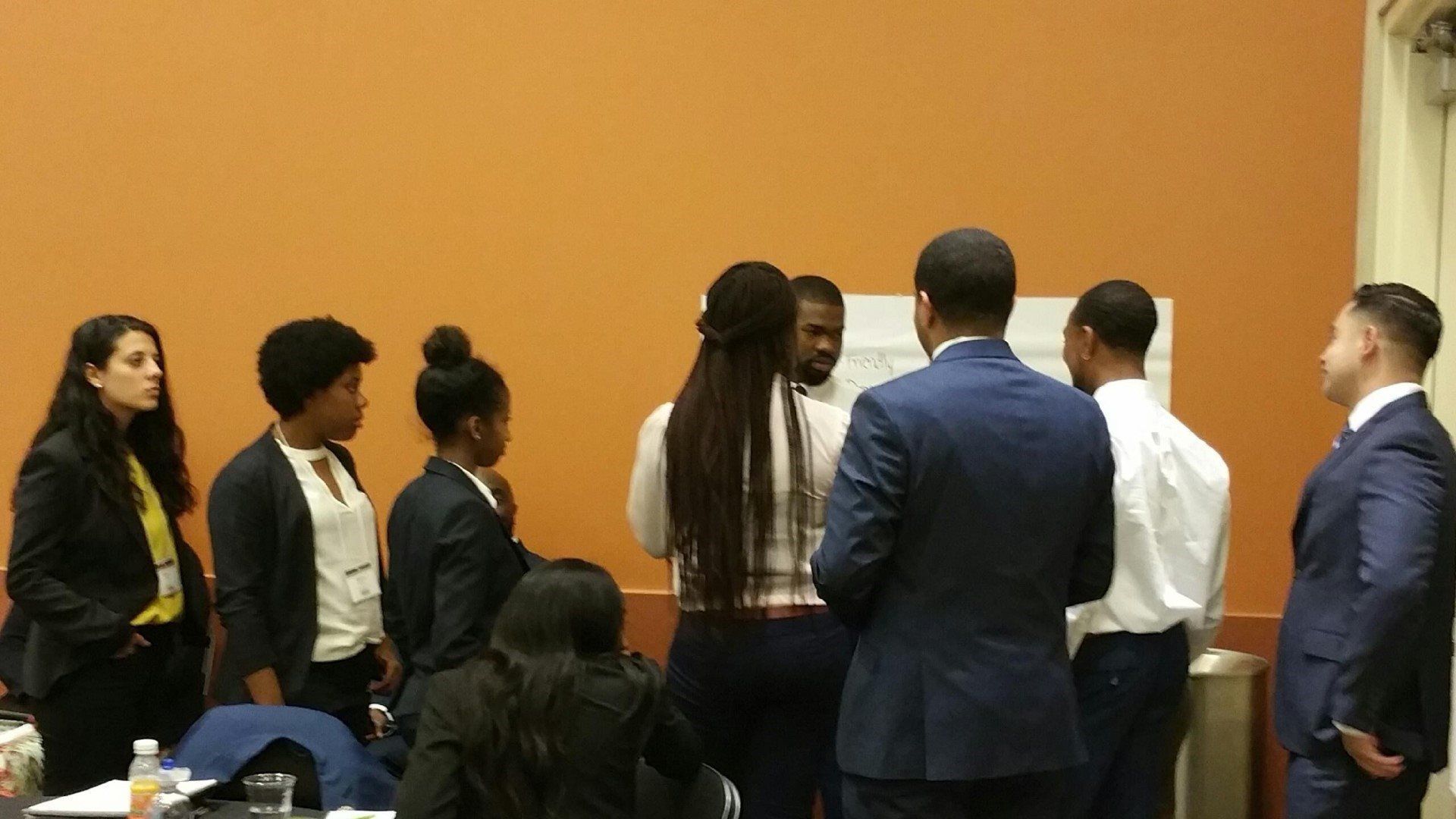 A group of people are standing in a room talking to each other.