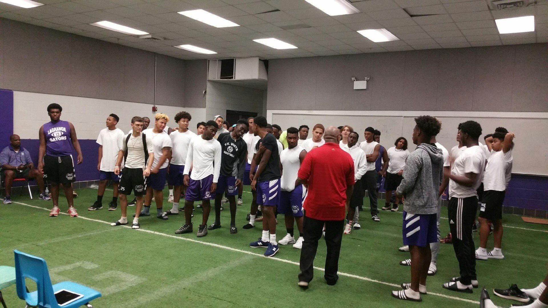 A group of young men are standing in a gym talking to each other.