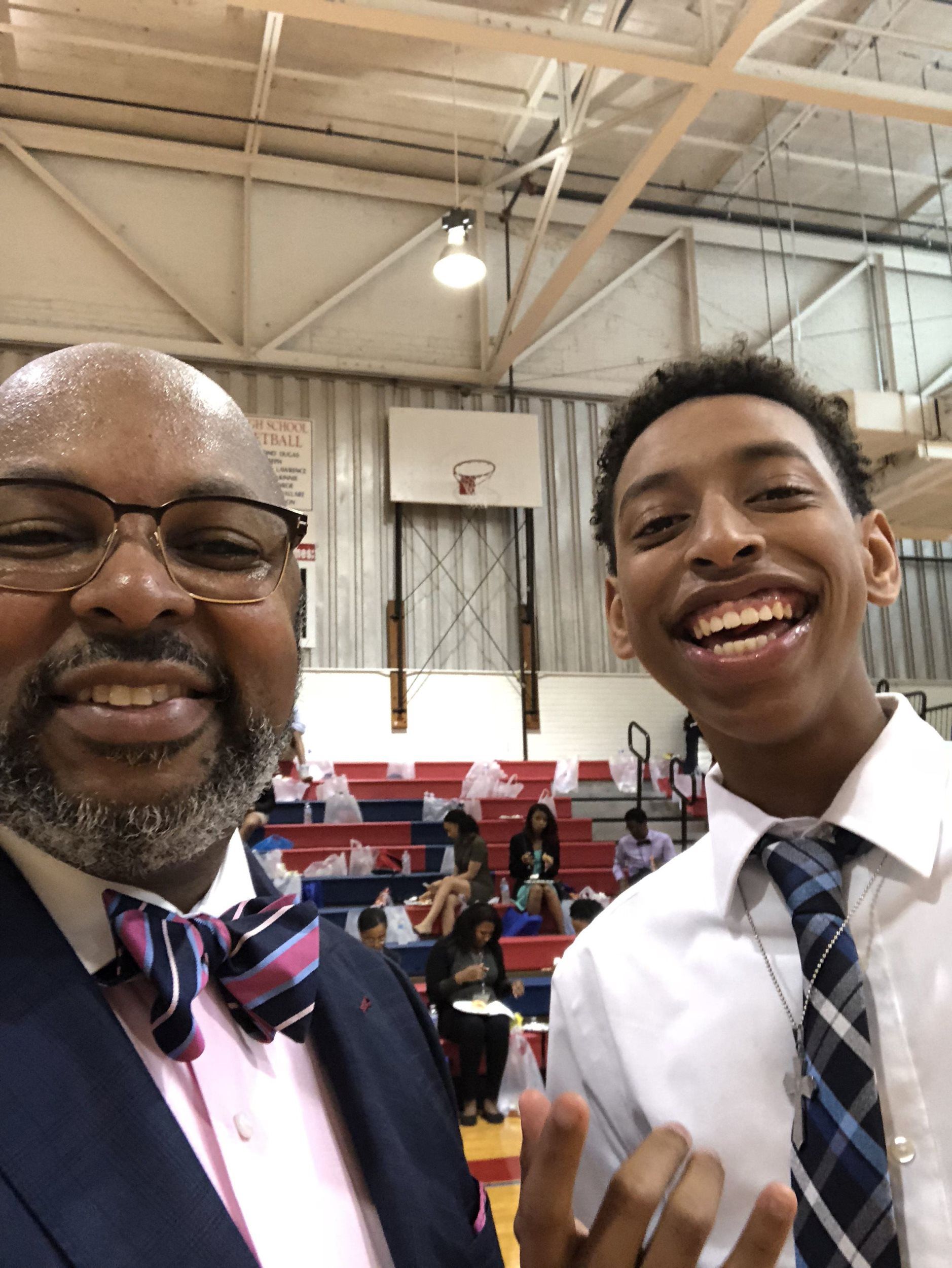 A man and a boy are posing for a picture in a gym