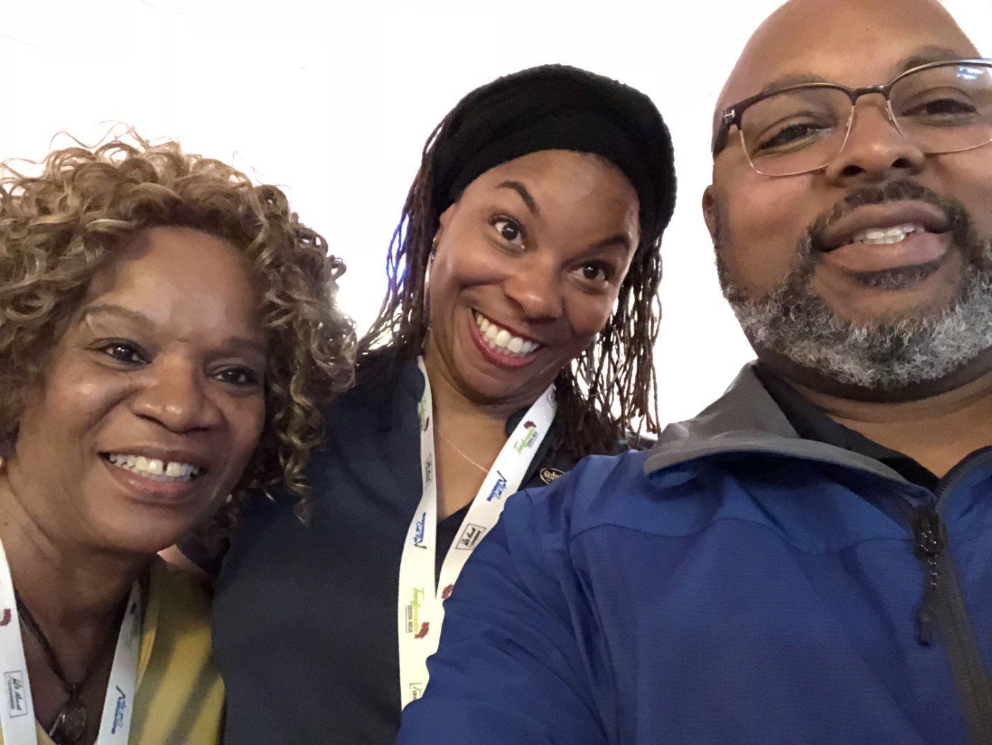 A man and two women are posing for a picture and the man is wearing glasses