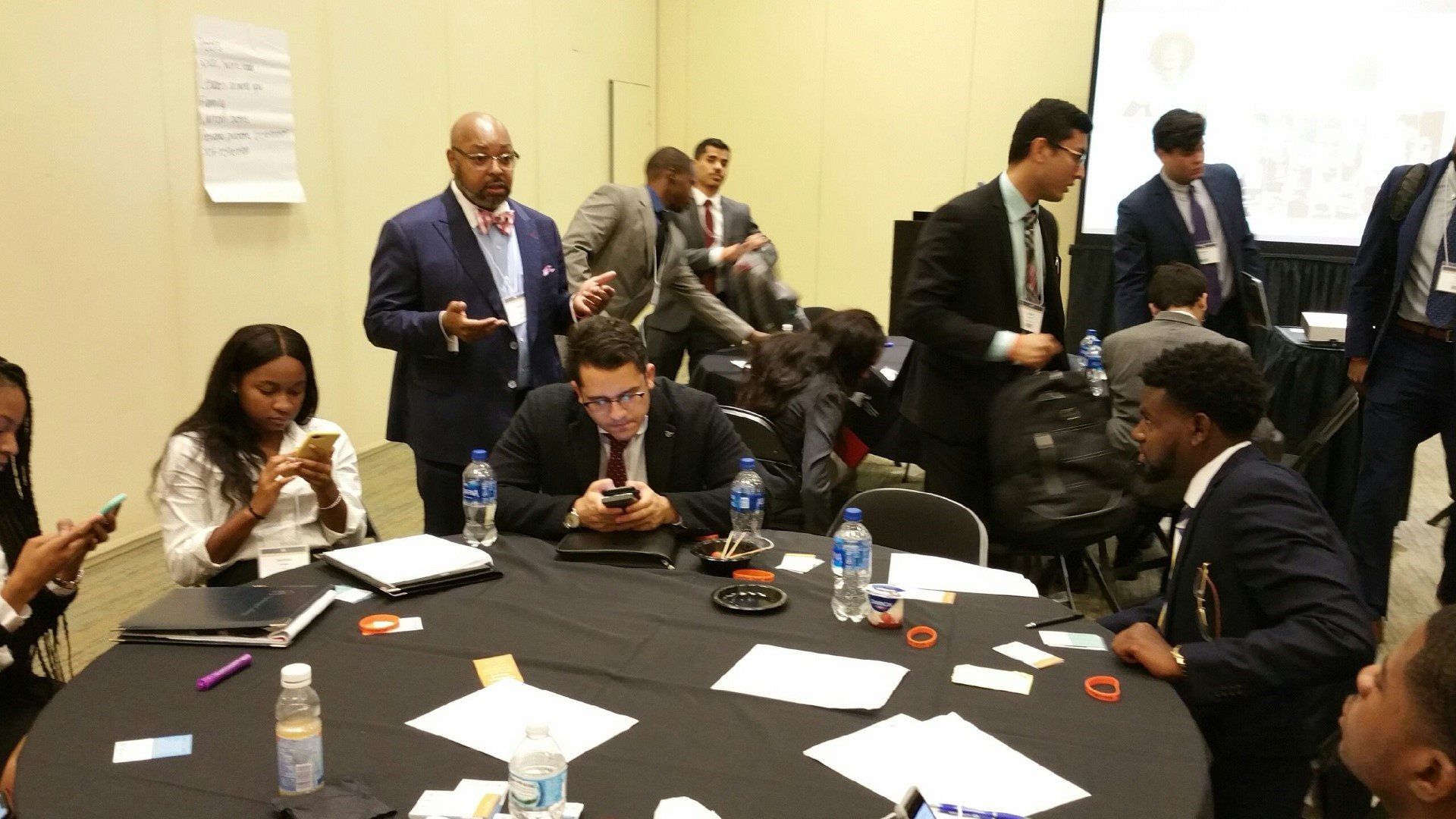 A group of people are sitting around a table looking at their phones.