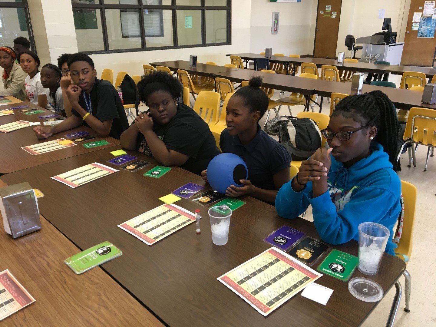 A group of young people are sitting at a table in a cafeteria.