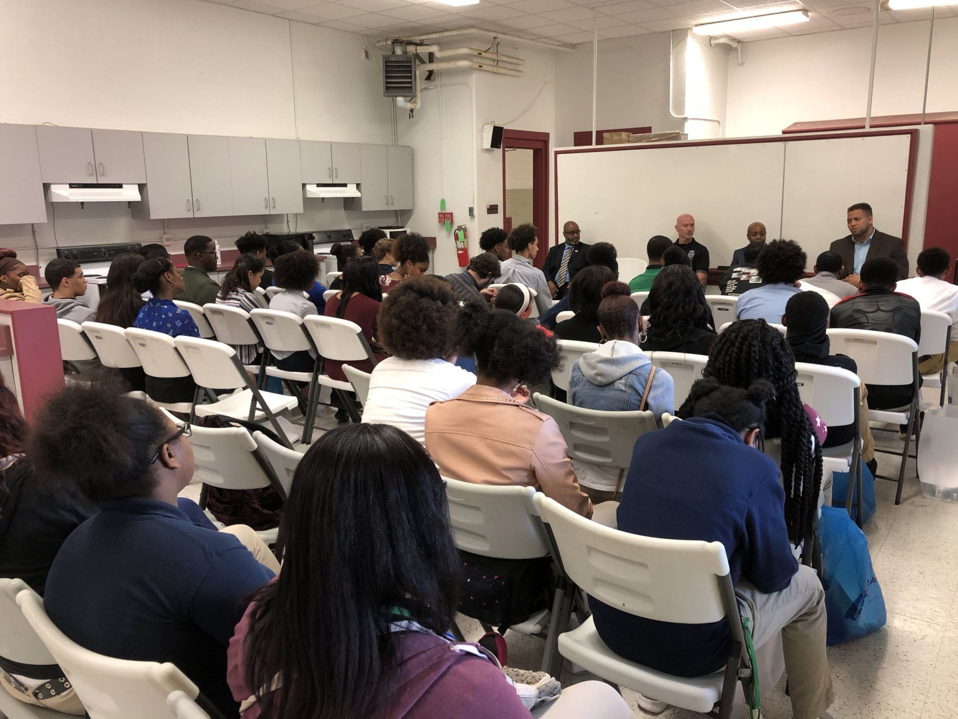 A large group of people are sitting in chairs in a room.