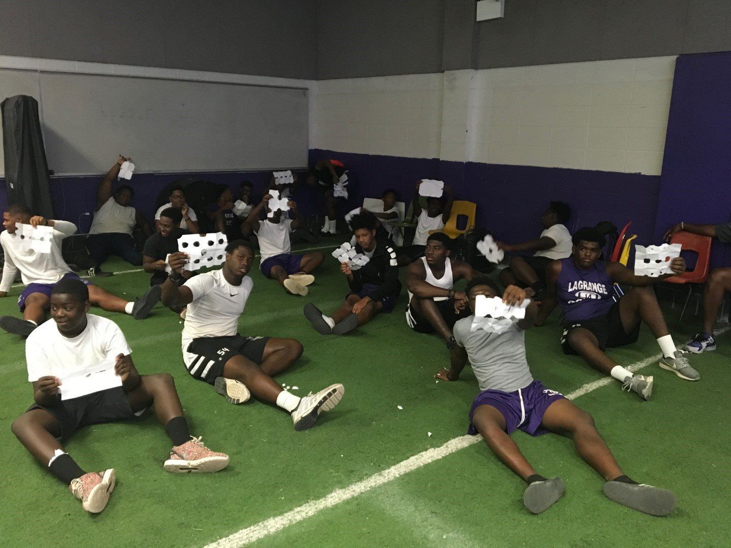 A group of young men are sitting on the floor stretching