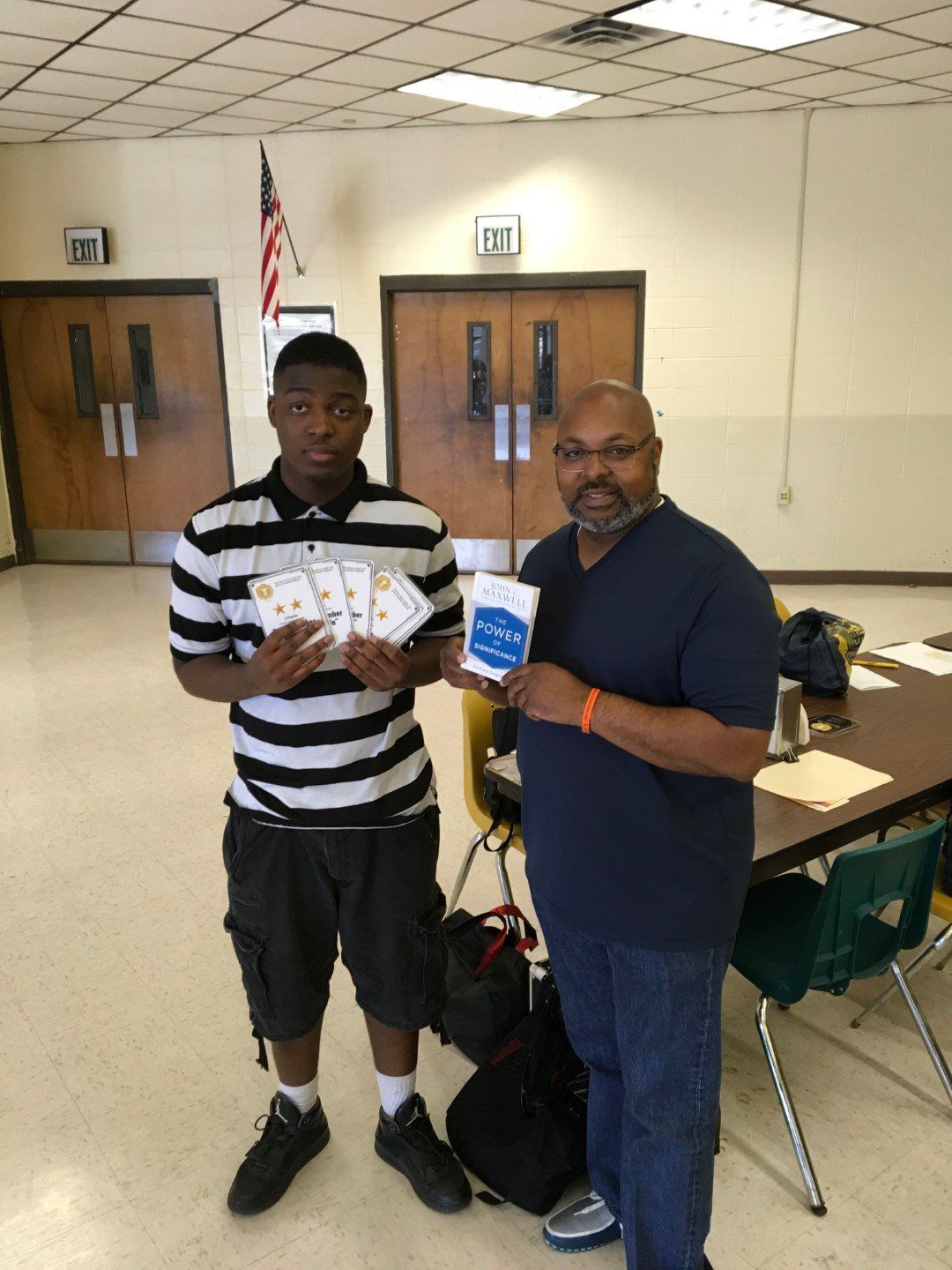 Two men standing next to each other in a room holding cards