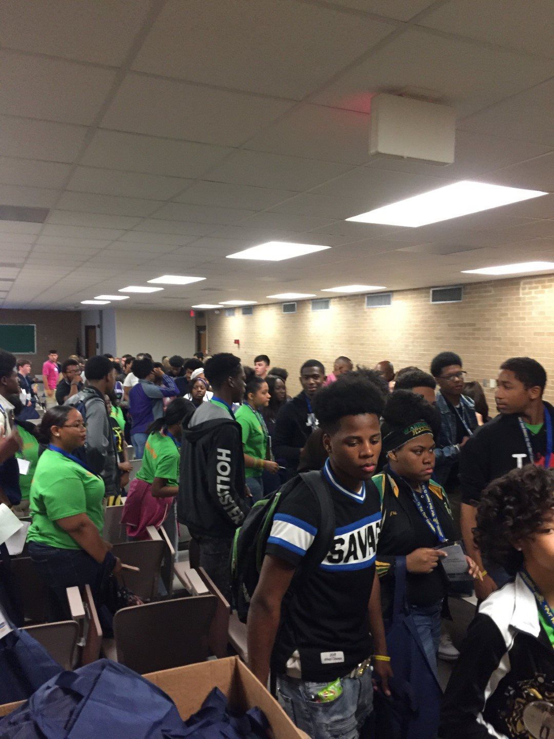 A group of people are standing in a room and one of them is wearing a shirt that says swag