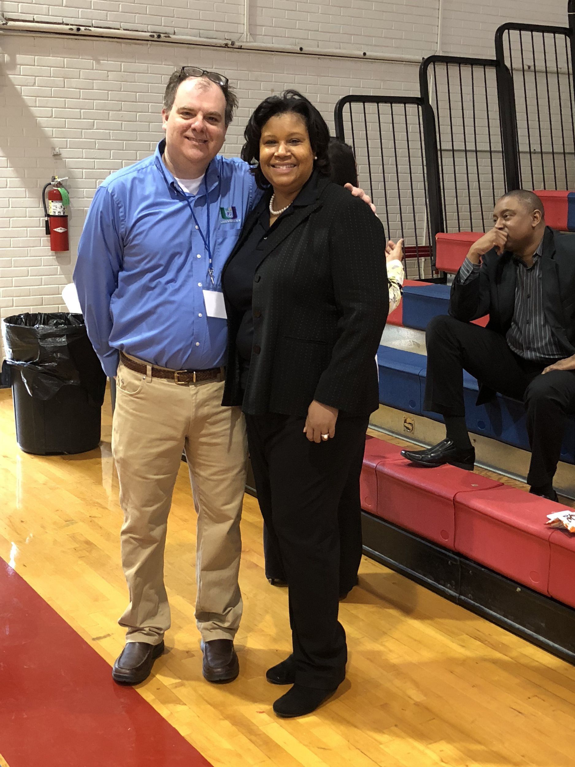 A man and a woman are posing for a picture on a basketball court.