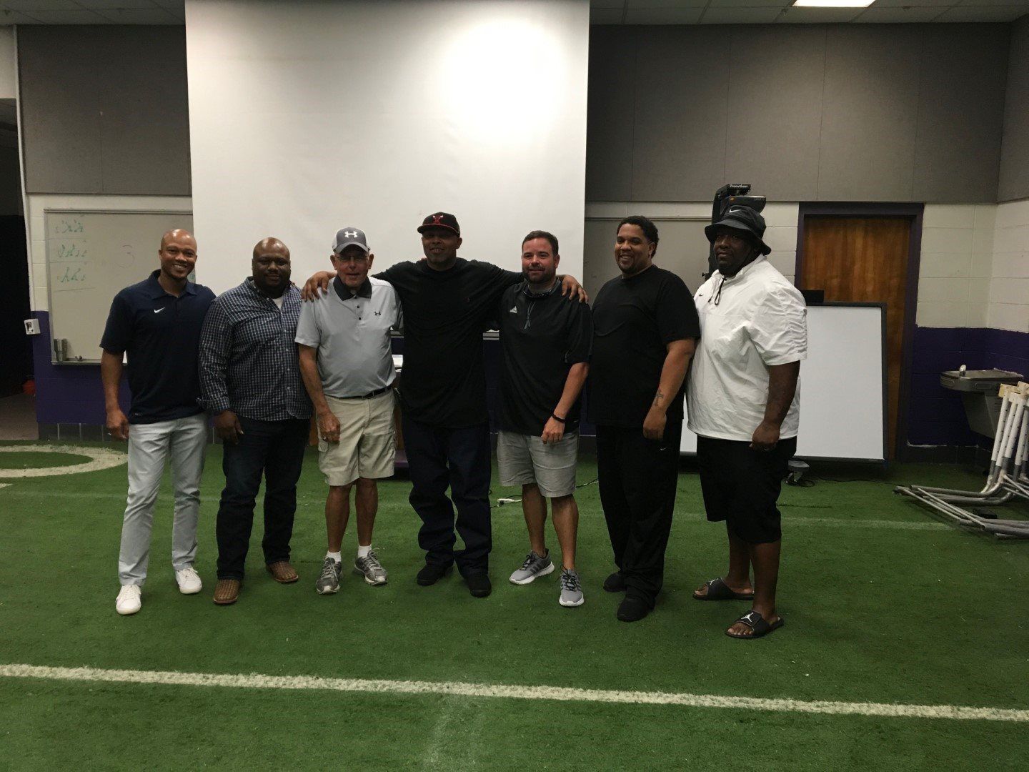 A group of men are posing for a picture on a football field.
