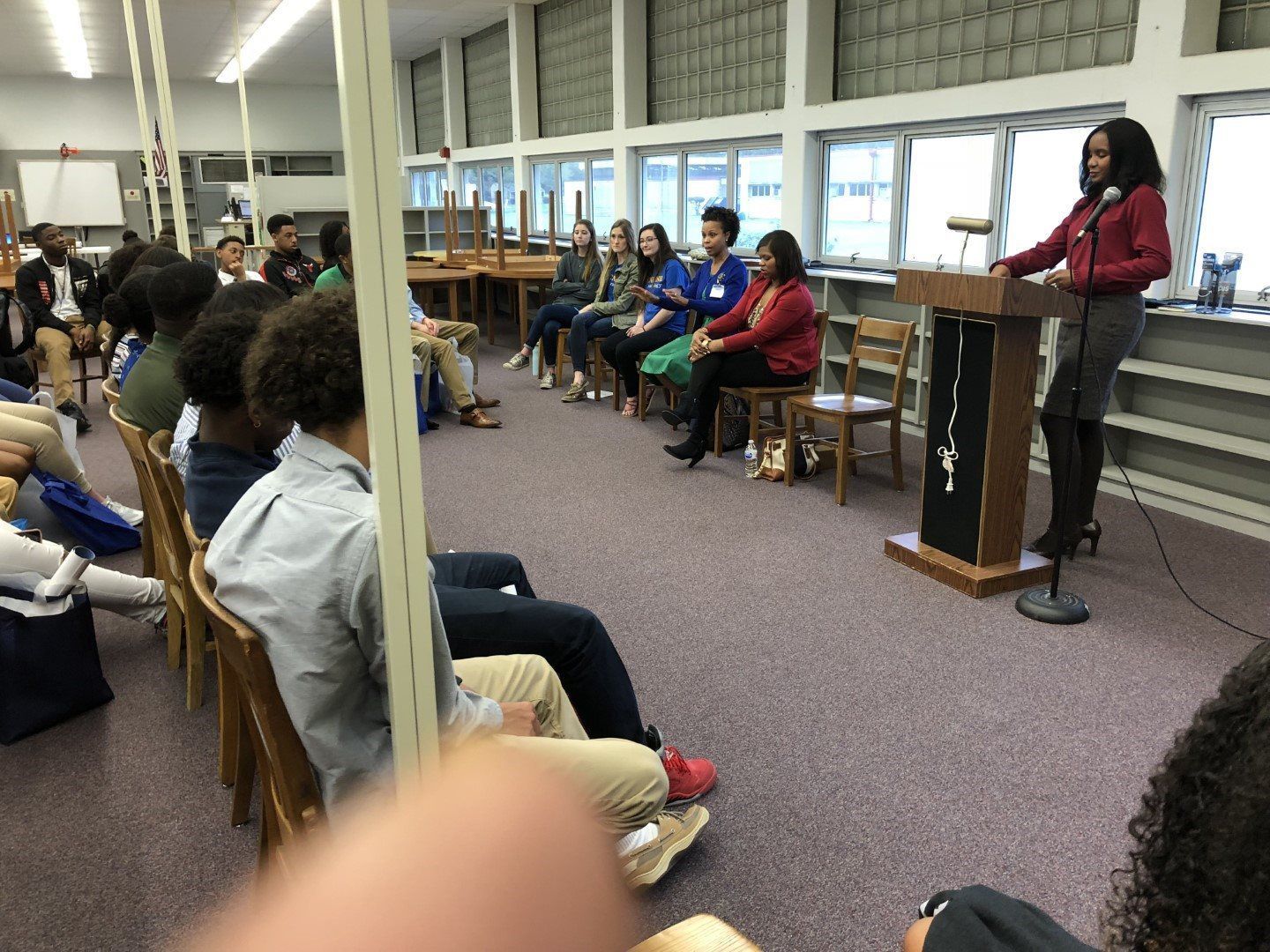 A woman is giving a speech at a podium in front of a group of people