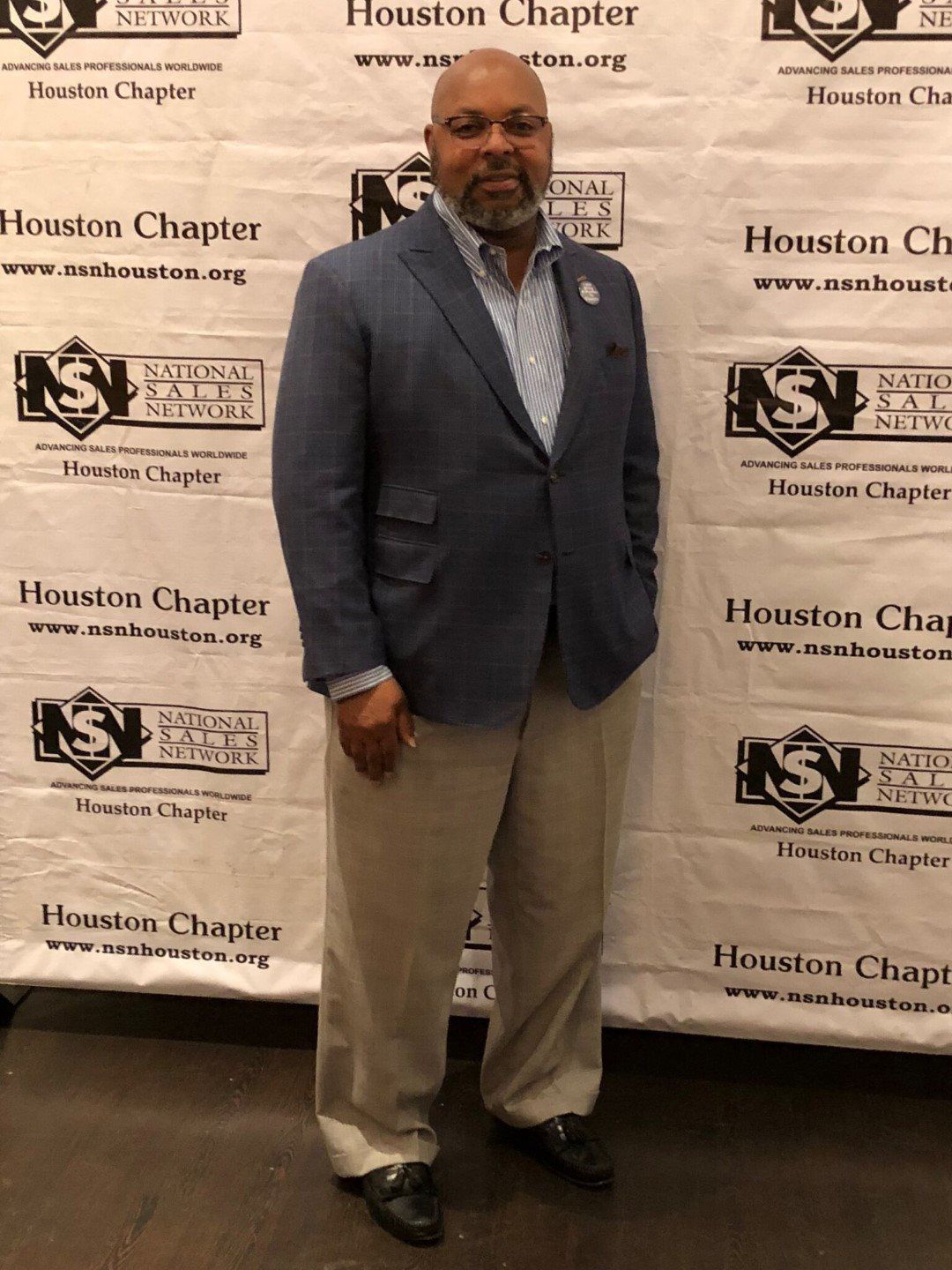 A man in a suit is standing in front of a houston chapter banner.