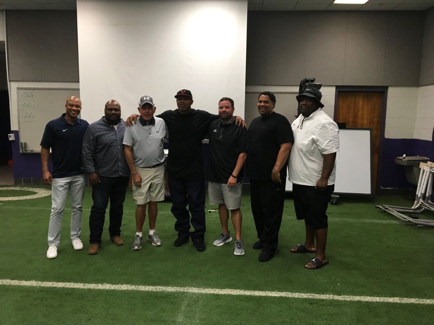 A group of men are posing for a picture on a football field.