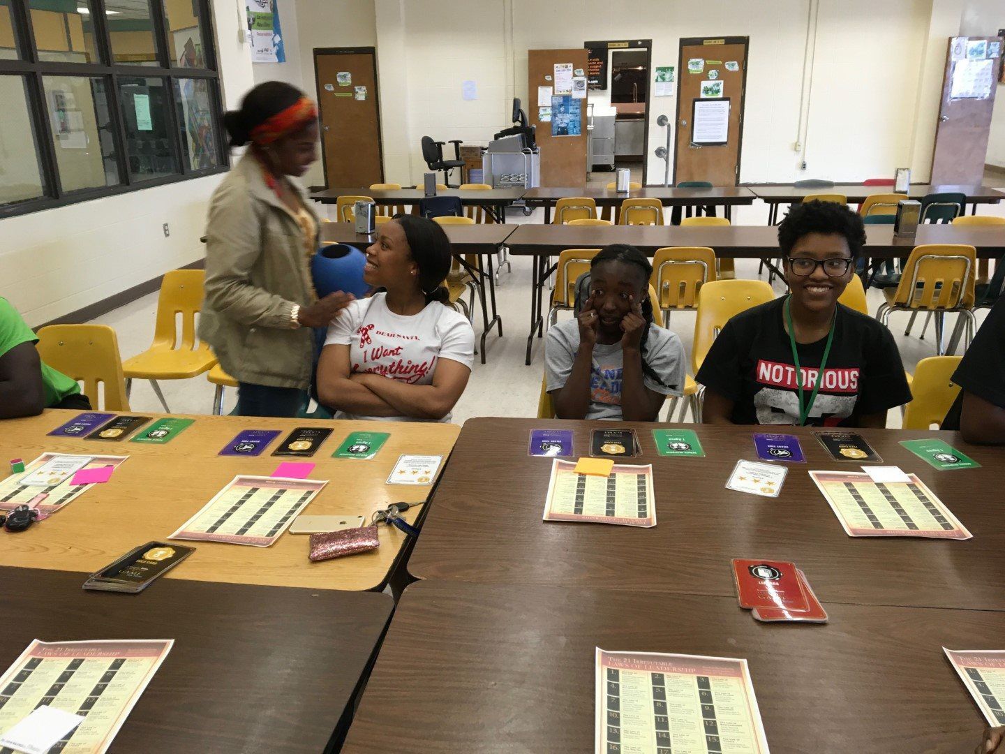 A group of children are sitting at a table with cards on it and one of them is wearing a shirt that says nothing