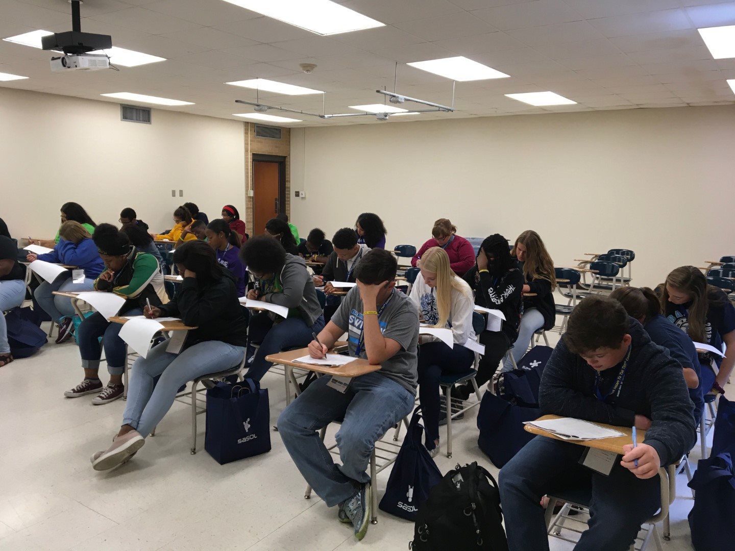 A group of students are sitting at desks in a classroom taking a test.