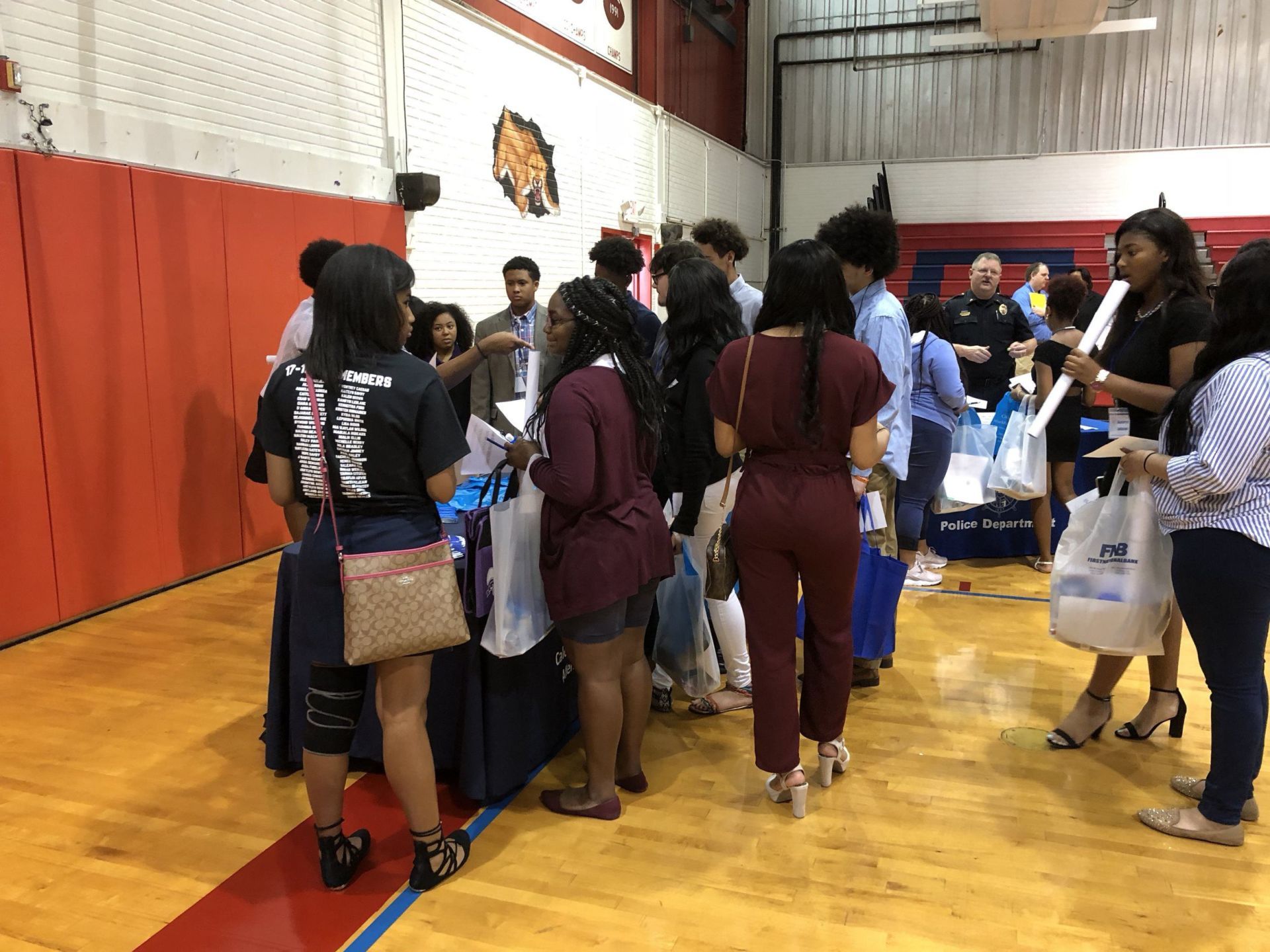 A group of people are standing around a table in a gym.