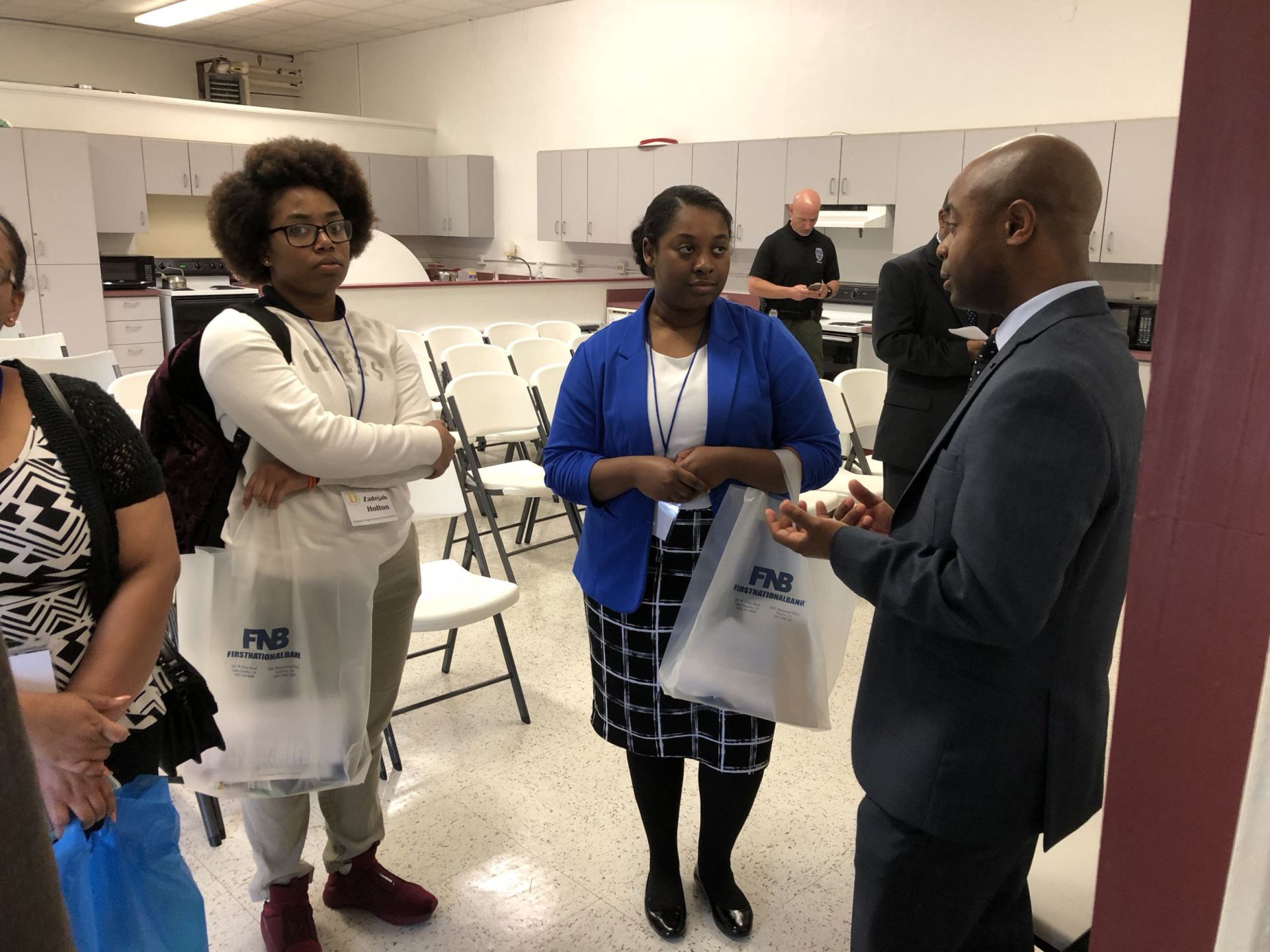 A group of people are standing in a room talking to each other.