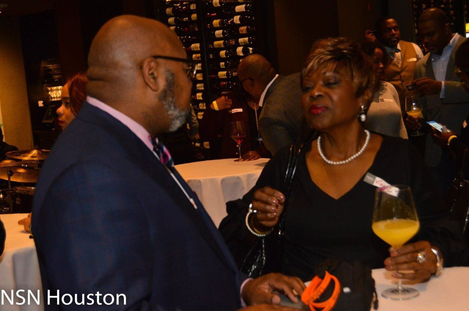 A man in a suit and tie is talking to a woman who is holding a glass of orange juice ..