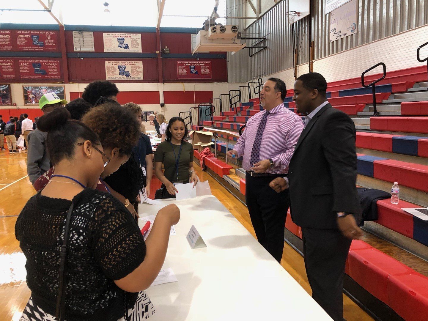 A group of people are standing around a table in a gym.